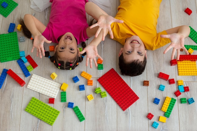 写真 幸せな男の子と小さな女の子の肖像画が床に横たわっています