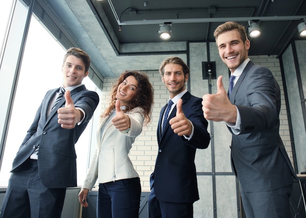 Фото Портрет счастливых бизнесменов, стоя в офисе, показывая большой палец вверх.