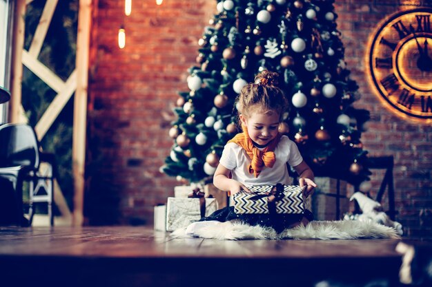 Портрет счастливой маленькой девочки с рождественскими подарками. концепция рождества