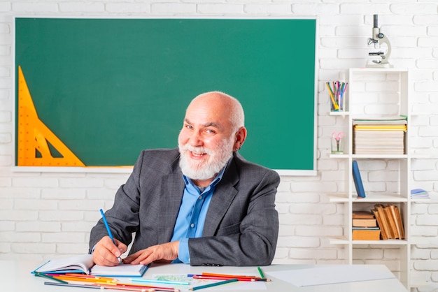 사진 교실에 앉아 있는 행복한 수석 교사의 초상화 그의 일을 사랑하는 쾌활한 교사 웃긴 노교수 웃는 선생님
