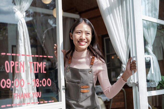 사진 portrait of happy waitress standing at restaurant entrancesmiling small business owner showing open sign in her shop