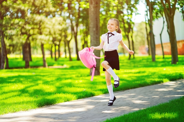 Фото Портрет счастливой молодой улыбающейся девушки носить школьный рюкзак за пределами начальной школы
