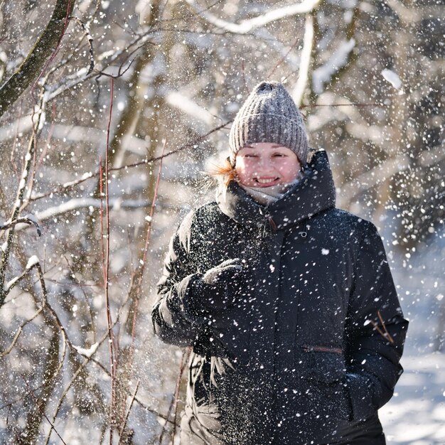 写真 冬の日に森を歩く幸せな若い女性の肖像画