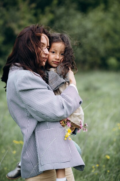 写真 フィールドで彼女の腕に娘を持つ流行に敏感な母親の肖像画。家族は一緒に楽しんでいます