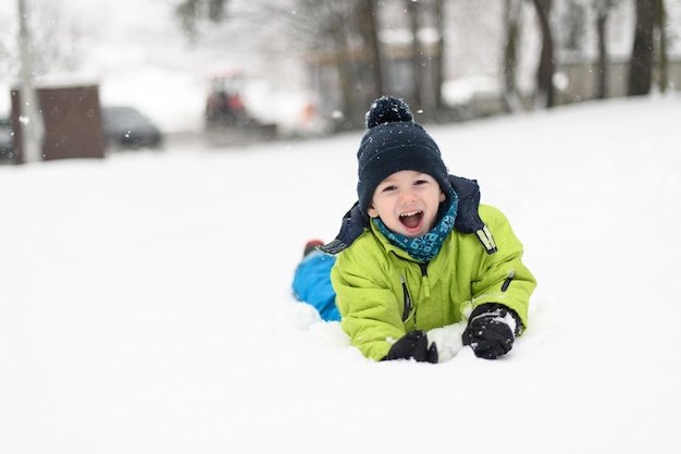 写真 雪の中に横たわる小さな幸せな少年の肖像画