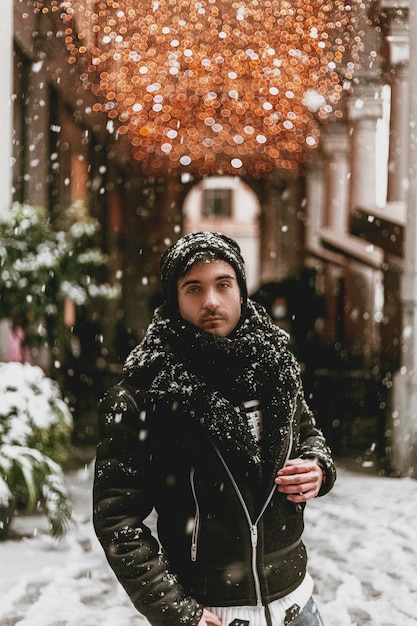Фото Портрет человека, стоящего в снегу напротив освещенного осветительного оборудования на открытом воздухе