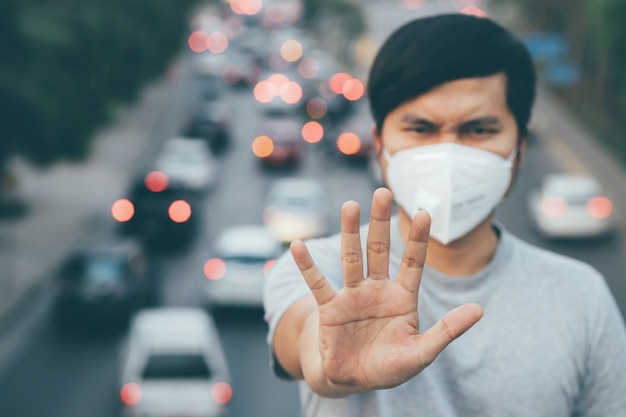 写真 屋外で顔の衛生的なマスクの鼻を身に着けている男の肖像画。エコロジー、大気汚染車、環境およびウイルス保護の概念、有毒なほこりに対するインフルエンザの健康は、健康への影響の都市をカバーしました。