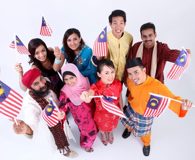 写真 白い背景にマレーシアの国旗を掲げる伝統的な服を着た人々の肖像画