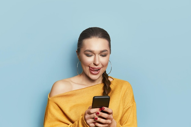 Портрет позитивной жизнерадостной девушки использует смартфон, выглядит копирайтом, делится новостями в социальных сетях