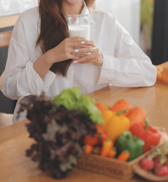 사진 부엌에서 화면을 보고 웃고 있는 테이블에 앉아 노트북 컴퓨터에 타이핑을 하고 있는 꽤 프리랜서 여성의 초상화