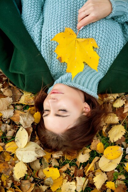 Фото Портрет красивой молодой женщины славянской внешности в темной повседневной одежде осенью, лежащей на осенних желтых листьях