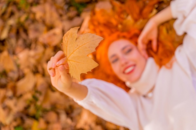 사진 숲 공원 웃는 가을 라이프 스타일에 나뭇잎에 누워 redhaired 여자의 초상화