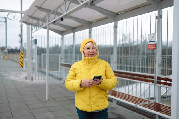 写真 電車駅で待つ間携帯電話を使っている女性の肖像画高品質の写真