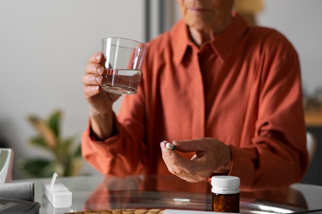 Фото Портрет пожилой женщины, принимающей лекарства дома