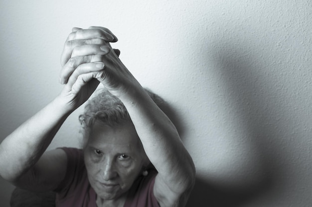 Фото Портрет пожилой женщины с руками, прижатыми к стене