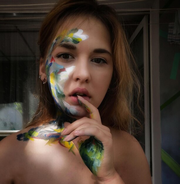 Фото Портрет молодой женщины без рубашки с краской на лице дома