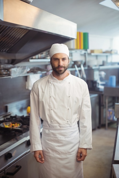 Портрет улыбающегося шеф-повара, стоящего на коммерческой кухне