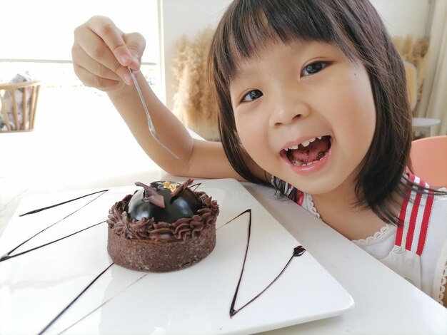 写真 チョコレートケーキを食べている笑顔の女の子の肖像画