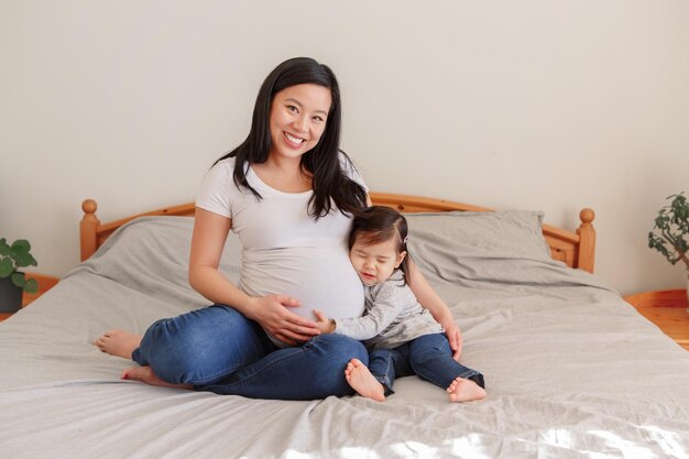 写真 ベッドに座っている娘と笑顔の妊婦の肖像画