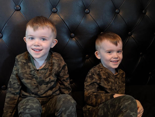 Фото Портрет улыбающихся близнецов, сидящих на диване