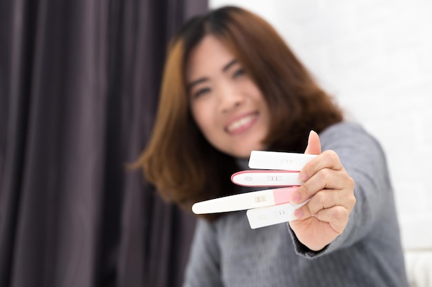 사진 집 에서 임신 테스트 키트를 들고 있는 웃는 여자 의 초상화