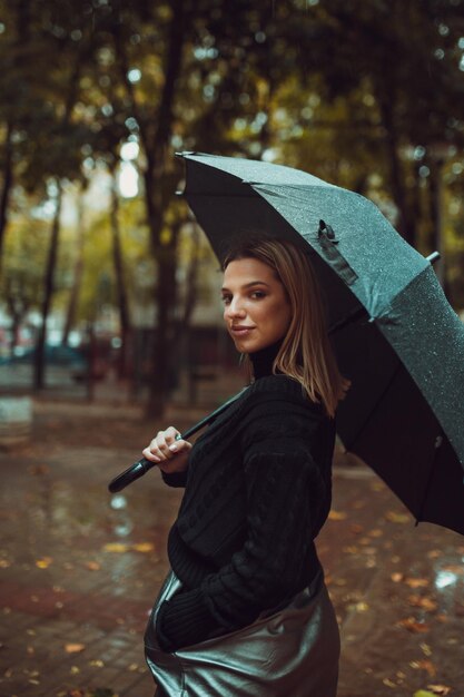 Фото Портрет улыбающейся молодой женщины с зонтиком в парке