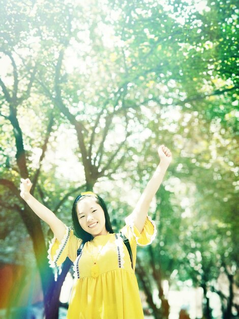 写真 木に寄りかかって立っている笑顔の若い女性の肖像画