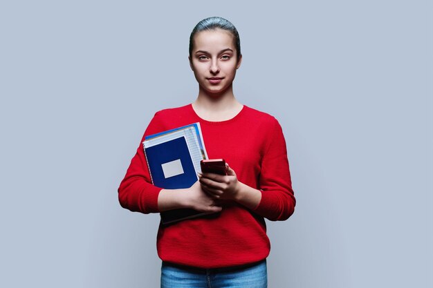 Фото Портрет студентки-подростка с смартфоном на сером фоне
