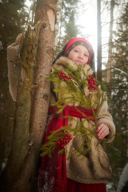 写真 厚いコートを着たティーンエイジャー女の子の肖像画赤いセーシュと冷たい間に明るいベリーをつけた杉の枝