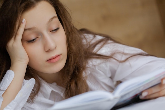 写真 ベッドに横たわって本を読んでいる10代の少女の肖像画
