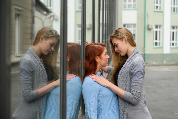 Фото Портрет двух лесбиянок, стоящих на улице и нежно прикасающихся друг к другу лгбт молодая любящая гей-пара девушка страстно прижимает свою спутницу жизни к зеркальной стене