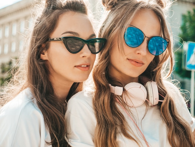 Фото Портрет двух молодых красивых улыбающихся хипстерских женщин в модной летней белой футболке