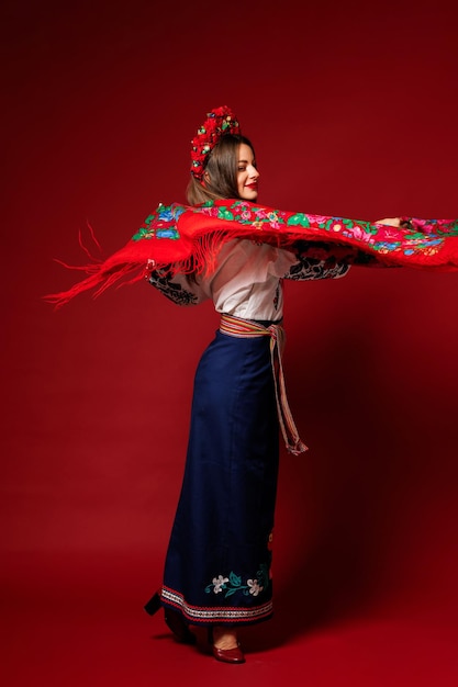 Фото Портрет украинки в традиционной этнической одежде и цветочном красном венке на фоне студии viva magenta крутит носовой платок украинское национальное вышитое платье называется вышиванка