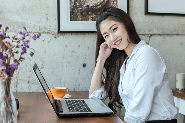 写真 テーブルの上のラップトップとコーヒーカップの女性の肖像画