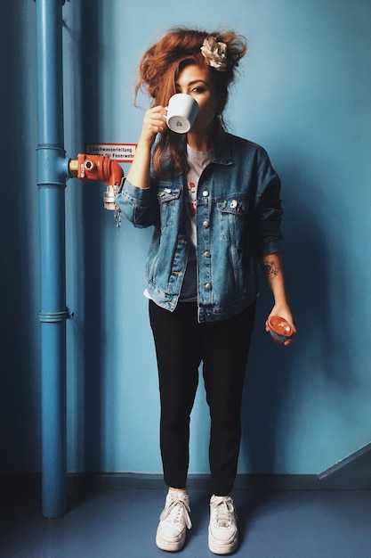 Фото Портрет женщины, пьющей, стоящей у стены