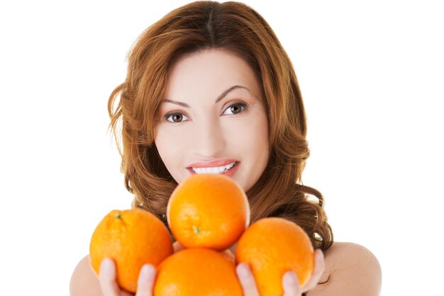 写真 白い背景にオレンジ色の果物を握っている女性の肖像画