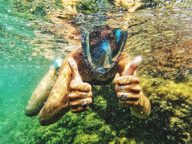 写真 海底で泳いでいるときに親指を上げている女性の肖像画