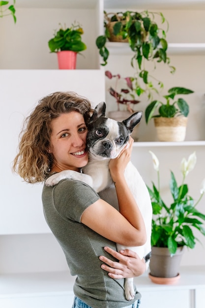 Фото Портрет женщины с бульдогом дома. вертикальный вид женщины, держащей ее собаку с растительным орнаментом