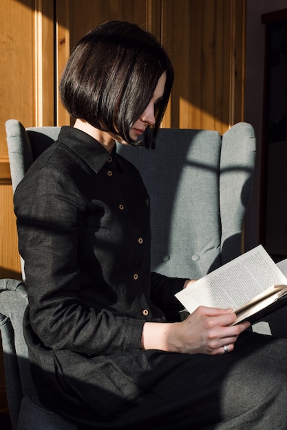 Фото Портрет молодой взрослой женщины, сидя в кресле и чтения книг