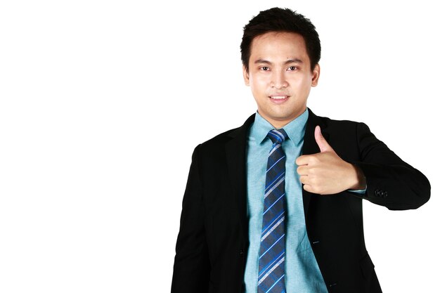 검은 양복을 입고 흰색 배경에 격리된 엄지손가락을 가리키며 웃고 있는 젊은 아시아 남자의 초상화.