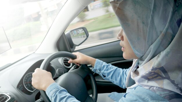 写真 アジアの若いイスラム教徒の女性が車を運転している肖像画見た目が良い起業家カーシェアリングコンセプト