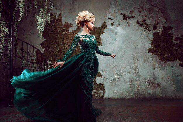 Портрет молодой привлекательной блондинке в красивом зеленом платье. текстурированный фон, интерьер. роскошная прическа
