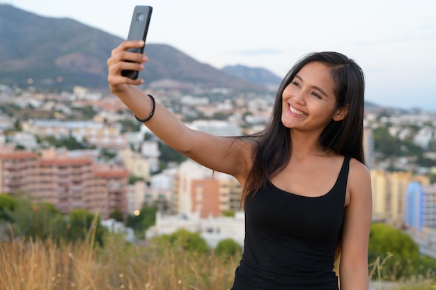Портрет молодой красивой азиатской туристической женщины на вершине холма с видом на город малага, испания