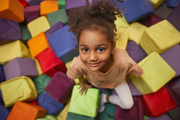 Фото Портрет молодой маленькой девочки, смотрящей вперед, играя в парке с кубиками