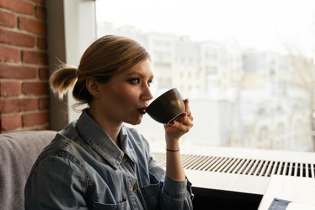 写真 ガラスの窓から飲む若い女性の肖像画