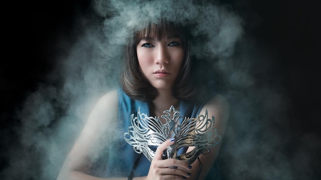 写真 黒い背景の煙の中に目隠しをしている若い女性の肖像画