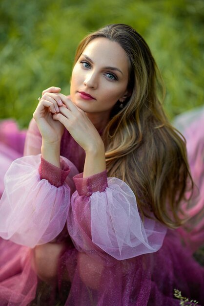 Фото Портрет молодой женщины в розовом мечтательном платье, сидящей в лесу