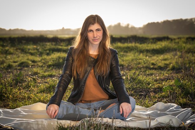Фото Портрет молодой женщины, сидящей на поле.