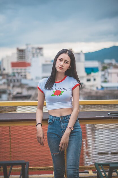 写真 街の雲の空に立っている若い女性の肖像画