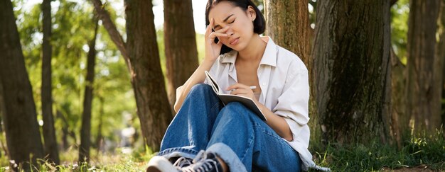 写真 木に寄りかかって立っている若い女性の肖像画